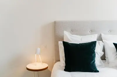 a bedroom with a bed with white pillows and a lamp at The 1880 Boutique Holiday Home in Antwerp