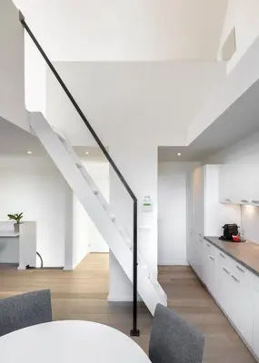 a white staircase in a room with a table and chairs at The 1880 Residence by Domani Hotels in Antwerp
