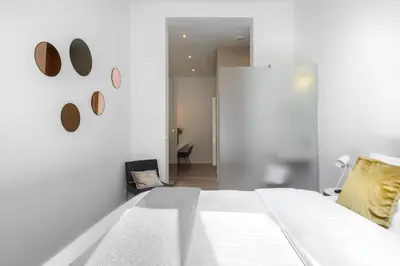 a white bedroom with a bed and a chair at The 1880 Residence by Domani Hotels in Antwerp