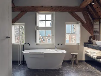 a white bath tub in a bathroom with windows at Botanic Sanctuary Antwerp - The Leading Hotels of the World in Antwerp