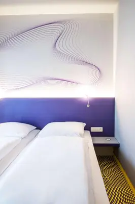 a bedroom with a bed with a purple and white wall at Prize by Radisson, Antwerp City in Antwerp