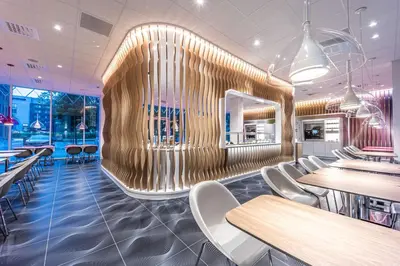 a restaurant with white chairs and a wooden wall at Prize by Radisson, Antwerp City in Antwerp