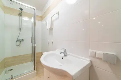 a white bathroom with a sink and a shower at La Hacienda in Vilvoorde