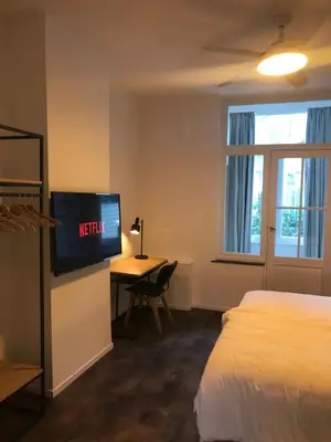 a hotel room with a bed and a desk with a television at Brussel House Basilic in Brussels