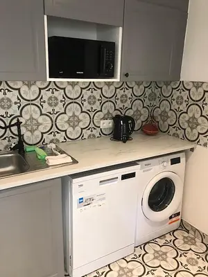 a kitchen with a washing machine under a microwave at Brussel House Basilic in Brussels