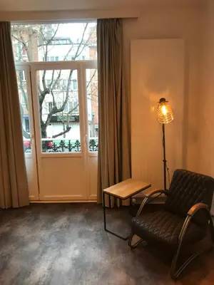 a living room with a chair and a window at Brussel House Basilic in Brussels