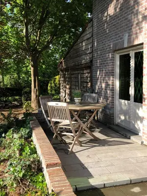 a wooden table and two chairs on a patio at T klein Kasteeltje Wetteren in Wetteren