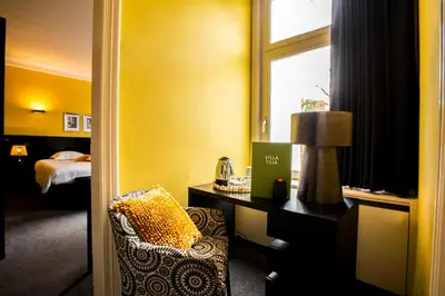 a hotel room with a chair and a desk and a window at Villa Tilia in Retie