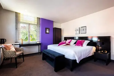 a bedroom with a large bed with purple walls at Villa Tilia in Retie