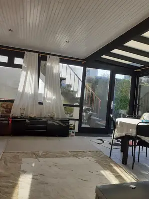 a living room with a table and white curtains at Residence Lilac in Brussels