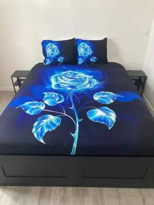 a bed with a blue blanket with a flower on it at Dreamland Apartments EU, Brussels in Brussels