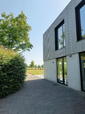 a building with a tree next to a sidewalk at HYTTA in Arendonk