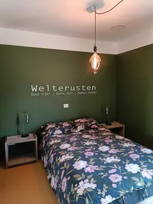a bedroom with a bed and a sign on the wall at HYTTA in Arendonk