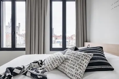 a bedroom with a bed with pillows and windows at MAISON12 - Design apartments with terrace and view over Ghent towers in Ghent