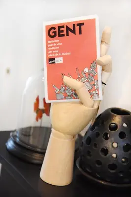a wooden hand holding a book on a table at MAISON12 - Design apartments with terrace and view over Ghent towers in Ghent