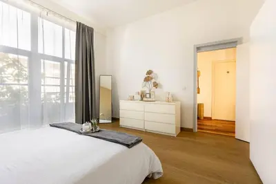 a white bedroom with a bed and a large window at Bel appart proche de gare du Midi, à côté du Centre Ville in Brussels