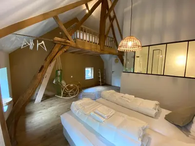 a living room with a large bed and a staircase at Quadratum 1769 in Herzele