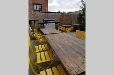 a wooden table and yellow chairs on a patio at Vakantiewoning in Mol centrum met eigen bar 