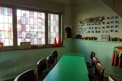 a dining room with green tables and chairs and windows at Vakantiewoning in Mol centrum met eigen bar 