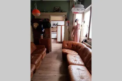a living room with brown leather couches and a kitchen at Vakantiewoning in Mol centrum met eigen bar 