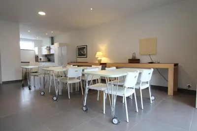 a room with tables and white chairs and a kitchen at NUVOLA VIEW in Zottegem