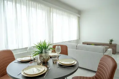 a dining room with a table and chairs and a couch at Brussels North - Pajot Apartments in Wemmel
