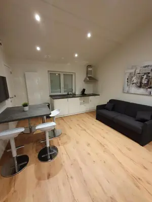 a living room with a black couch and a table at Brussels North - Pajot Apartments in Wemmel