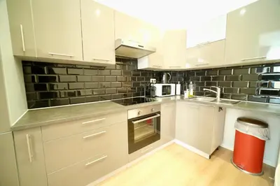 a kitchen with white cabinets and a red trash can at Smart Appart - City in Brussels
