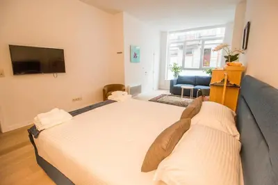 a large bed in a room with a couch and a tv at Smart Appart - City in Brussels