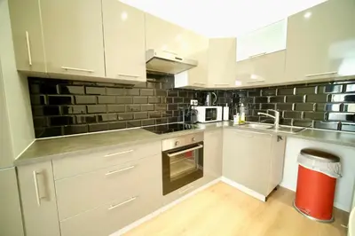 a kitchen with white cabinets and a red trash can at Smart Appart - City in Brussels