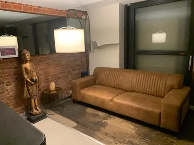 a living room with a couch and a statue at nice and cosy place with jacuzzi and sauna to relax in the centre of antwerp in Antwerp
