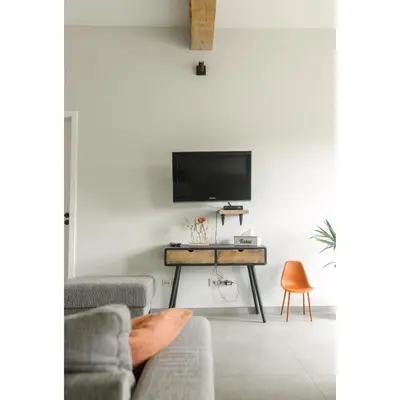 a living room with a table and a tv on a wall at Lianko - Vakantiewoning in Bekkevoort