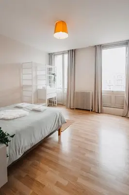 a white bedroom with a bed and a large window at Central and Cozy in Brussels in Brussels