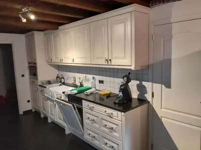 a kitchen with white cabinets and a black counter top at Lemen huis Houwaart in Tielt