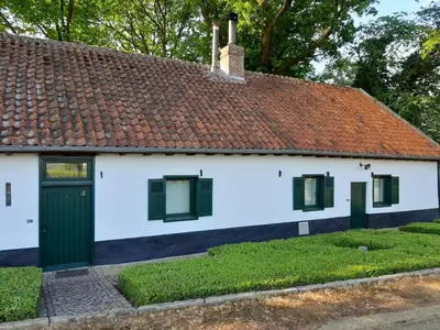 a white house with a red roof and green doors at Lemen huis Houwaart in Tielt