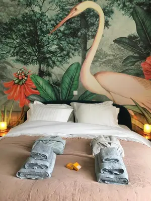 a bed with towels and a painting of a flamingo at Koeketiene Rooms in Ghent