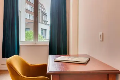 a wooden table with a book on it next to a window at Koeketiene Rooms in Ghent