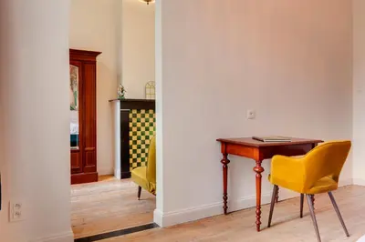 a room with a table and a yellow chair at Koeketiene Rooms in Ghent