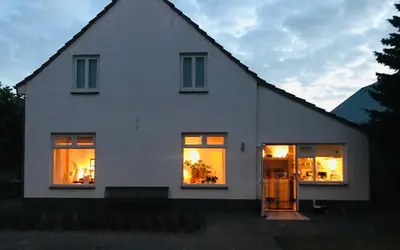 a white house with lights in the windows at De Morgenstond in Baarle-Hertog