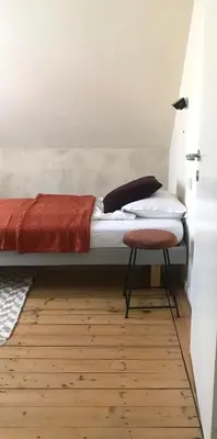 a bed in a room with a stool next to it at De Morgenstond in Baarle-Hertog