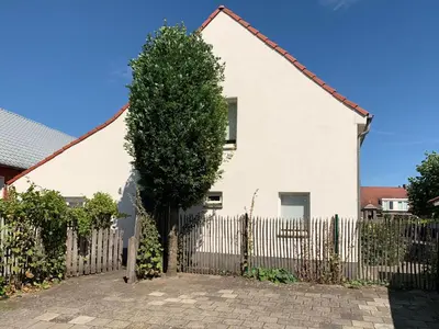 a white house with a fence and a tree at De Morgenstond in Baarle-Hertog