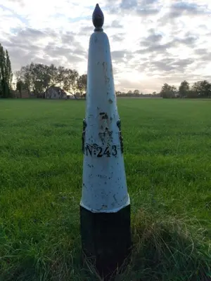a white cone sitting in the grass in a field at Bij grenspaal 243 in Essen