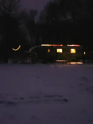 a bus parked in a snowy field at night at Bij grenspaal 243 in Essen