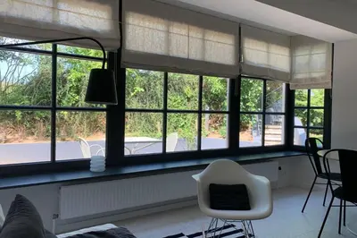a living room with windows and a white chair at Uccle, Pavillon Vert in Brussels