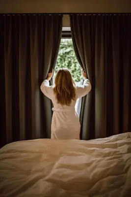 a woman is looking out of a window at BnB Manere in Grimbergen