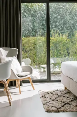 a bedroom with a bed and a chair and a window at BnB Manere in Grimbergen
