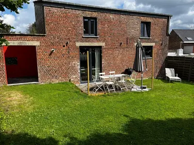 a brick building with a table and an umbrella at Jolie maison avec jardin. in Hoeilaart