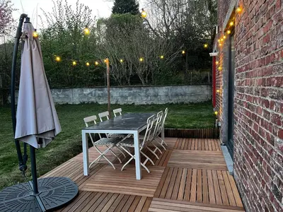 a table and chairs on a wooden deck with an umbrella at Jolie maison avec jardin. in Hoeilaart