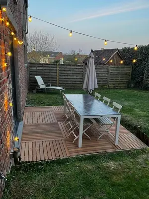 a table and chairs on a wooden deck with an umbrella at Jolie maison avec jardin. in Hoeilaart