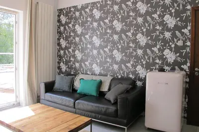 a black leather couch in a living room with a floral wallpaper at Brussels Downtown with terrace in Brussels